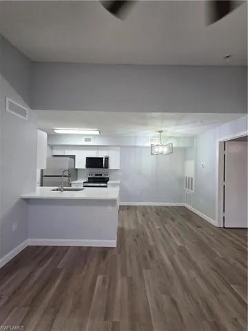 Kitchen featuring white cabinetry, stove, a peninsula, dark wood-style flooring, and fridge