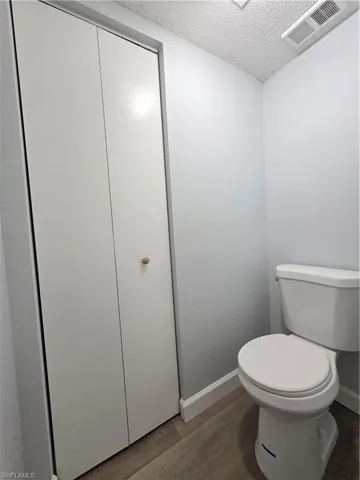 Bathroom with a textured ceiling and dark wood-style flooring