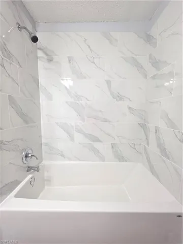 Full bath featuring bathing tub / shower combination and a textured ceiling
