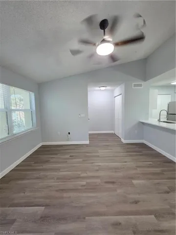 Unfurnished living room featuring dark wood-type flooring and ceiling fan