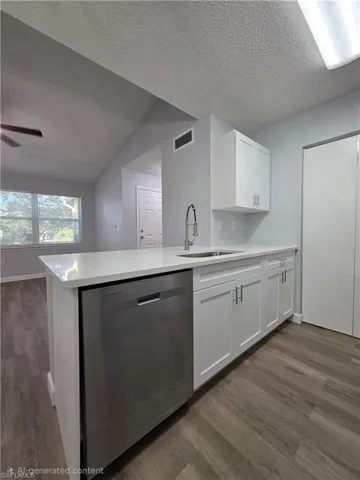 Kitchen featuring dishwasher, white cabinets, a peninsula, dark wood-style flooring, and light stone countertops
