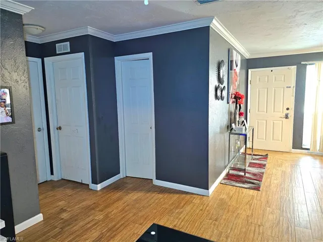 Foyer entrance with crown molding, hardwood / wood-style floors, and a textured ceiling