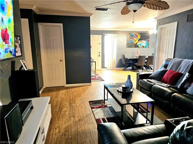Living room with crown molding, light wood-type flooring, and ceiling fan