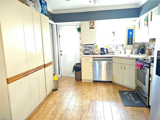 Kitchen featuring light hardwood / wood-style floors, decorative backsplash, crown molding, and stainless steel appliances