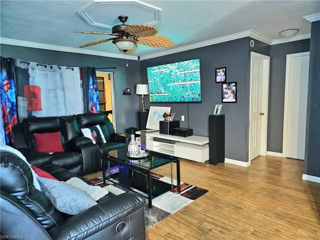 Living room featuring ceiling fan, wood-type flooring, and ornamental molding