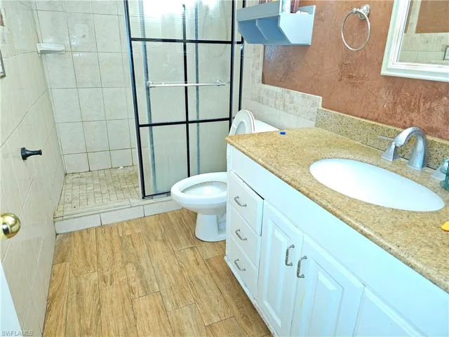 Bathroom with a shower with shower door, vanity, and toilet