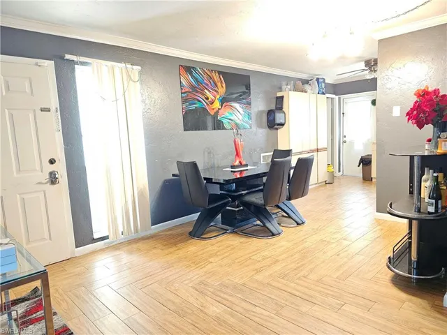 Dining room with crown molding, light parquet flooring, and ceiling fan