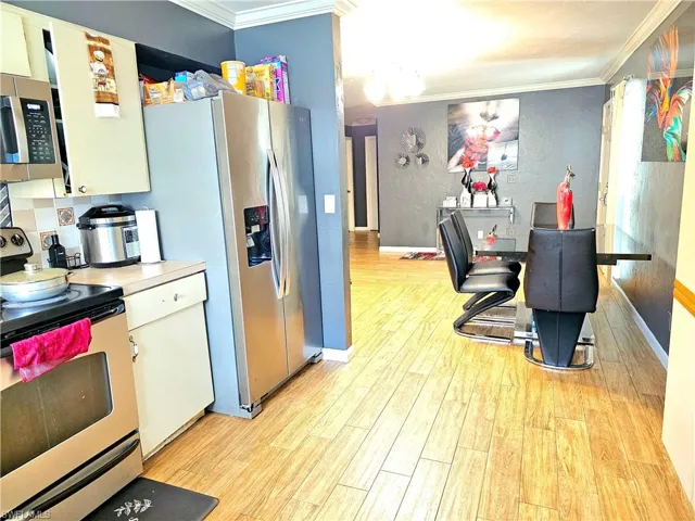 Kitchen with crown molding, stainless steel appliances, and light hardwood / wood-style flooring