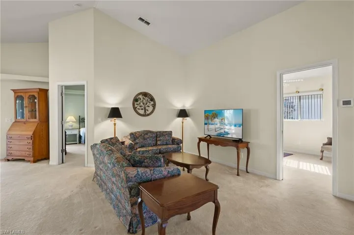 Living room featuring high vaulted ceiling and light carpet