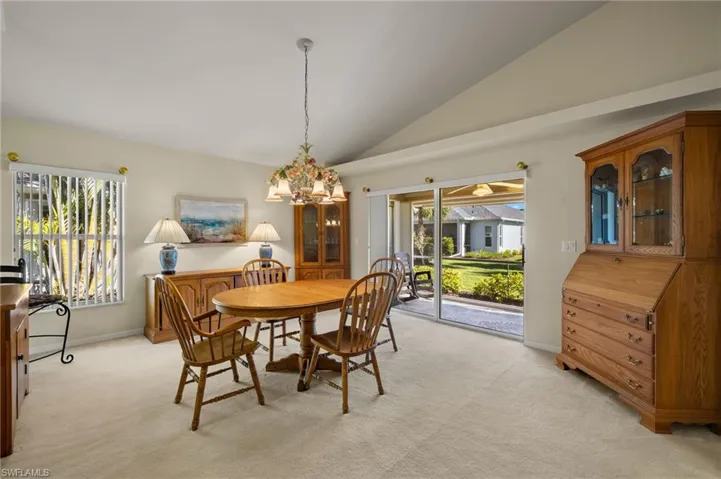Dining space with an inviting chandelier, light colored carpet, high vaulted ceiling, and plenty of natural light
