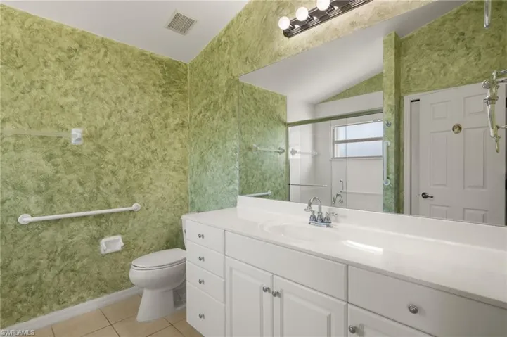 Bathroom featuring toilet, a shower with door, tile patterned floors, and vanity