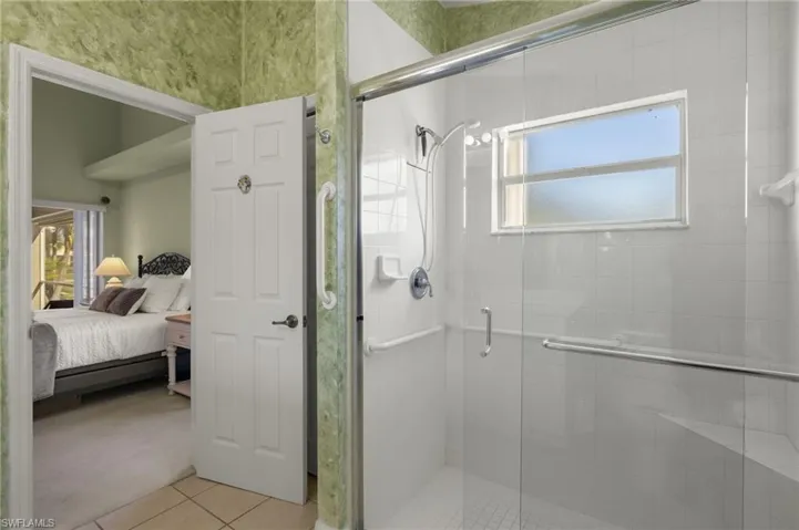 Bathroom featuring tile patterned flooring, a shower with shower door, and plenty of natural light