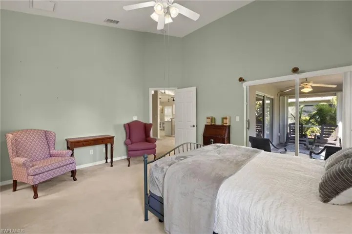Bedroom with ceiling fan, a towering ceiling, light carpet, and access to exterior