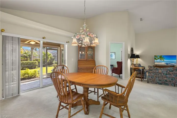 Carpeted dining area featuring high vaulted ceiling and a notable chandelier