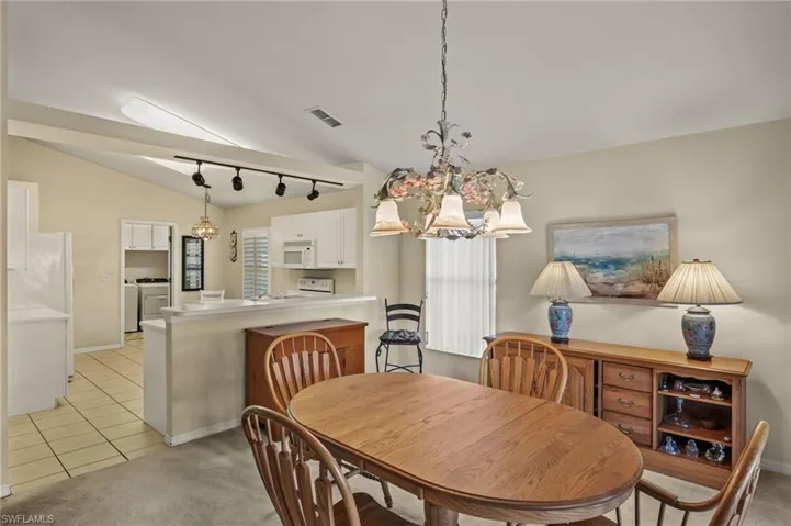 Tiled dining room featuring washer / clothes dryer, an inviting chandelier, lofted ceiling, and plenty of natural light