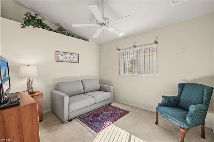 Carpeted living room featuring vaulted ceiling and ceiling fan