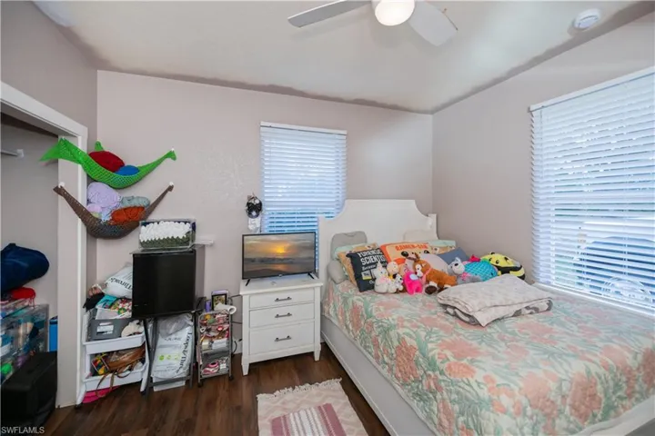 Bedroom featuring dark wood-type flooring, ceiling fan, and multiple windows