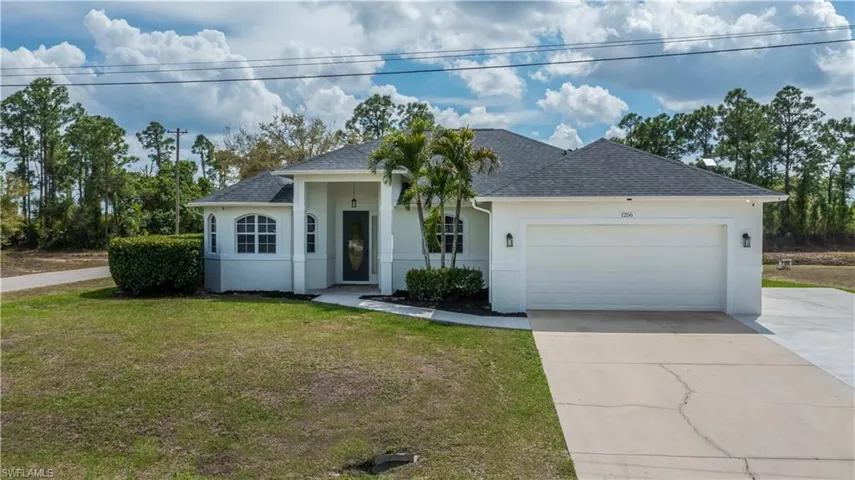 Ranch-style house with roof with shingles, stucco siding, an attached garage, a front lawn, and driveway