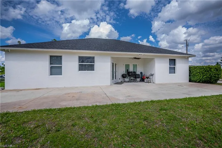 Back of property featuring a yard, a patio, a ceiling fan, stucco siding, and roof with shingles
