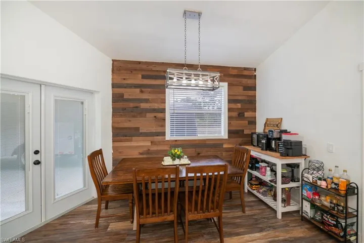 Dining room featuring wood walls, dark wood finished floors, an accent wall, and french doors