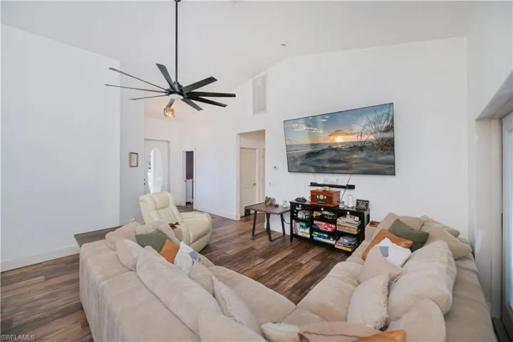 Living area featuring dark wood-style floors, lofted ceiling, and a ceiling fan