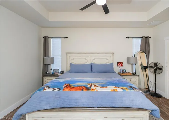 Bedroom featuring wood finished floors, ceiling fan, and a tray ceiling