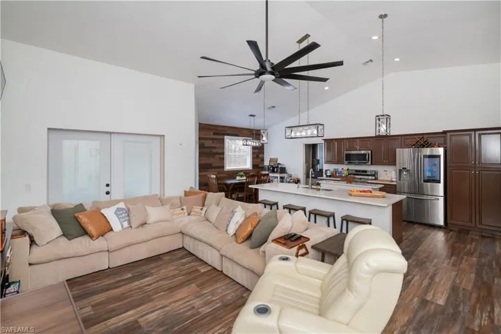 Living area featuring wood walls, vaulted ceiling, a ceiling fan, french doors, and dark wood-type flooring