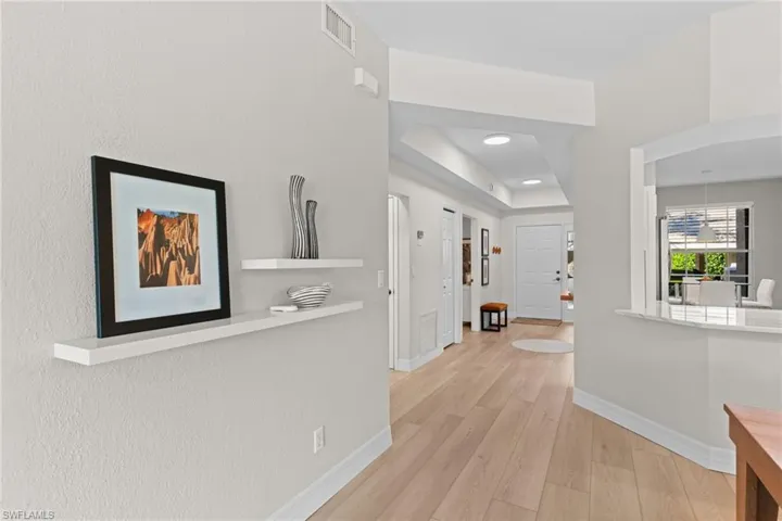 Corridor featuring light wood-style floors, recessed lighting, and a tray ceiling