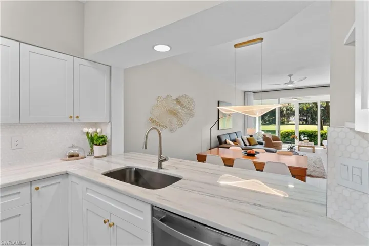 Kitchen featuring backsplash, light stone countertops, white cabinets, and dishwasher