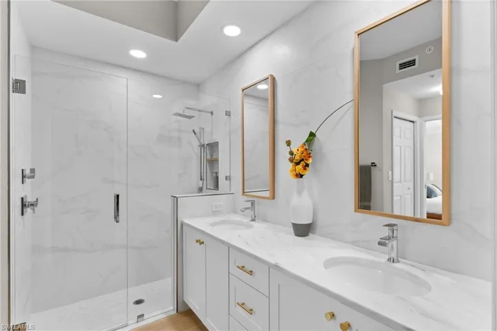 Ensuite bathroom with double vanity, a marble finish shower, and recessed lighting