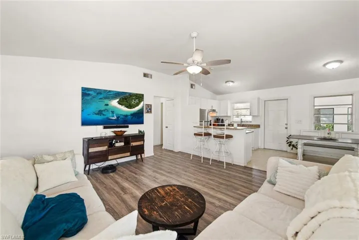 Living area featuring ceiling fan, dark wood-type flooring, and lofted ceiling