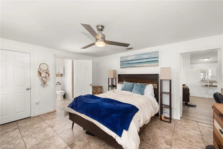Bedroom featuring a ceiling fan, ensuite bath, and light tile patterned floors