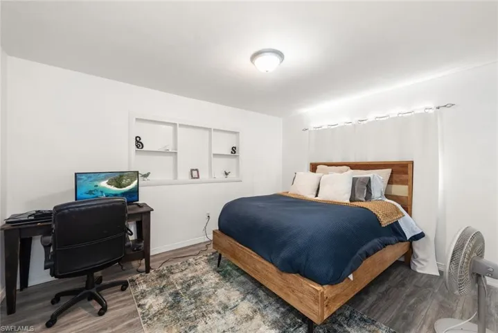 Bedroom with wood finished floors and an office area