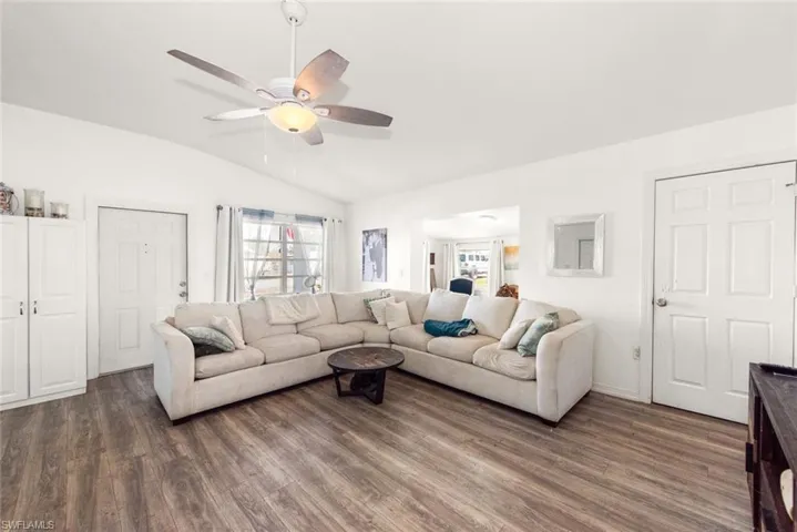 Living room with vaulted ceiling, dark wood-style floors, and ceiling fan