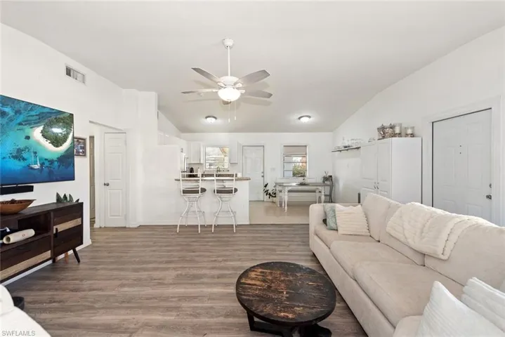 Living area featuring lofted ceiling, a ceiling fan, and light wood-type flooring