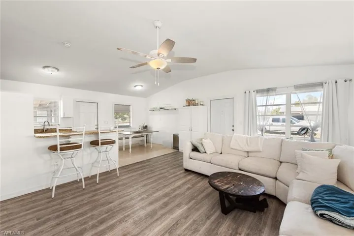 Living room with vaulted ceiling, dark wood finished floors, and a ceiling fan