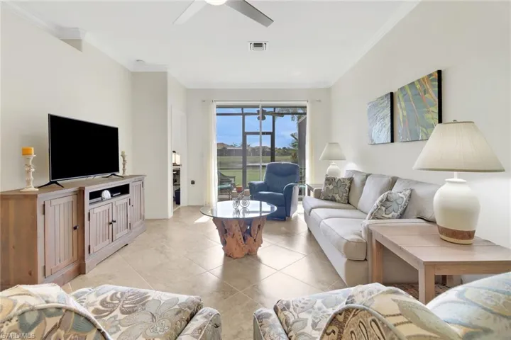 Tiled living room featuring ceiling fan and crown molding