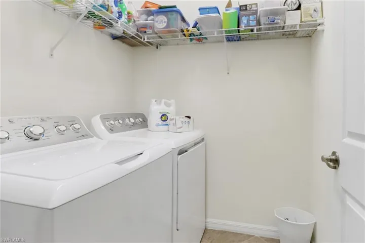 Clothes washing area with independent washer and dryer and light tile patterned floors