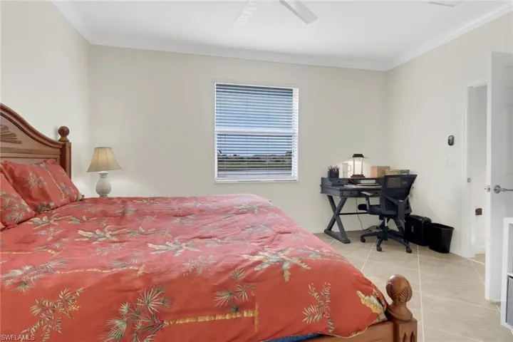 Tiled bedroom featuring ceiling fan and crown molding