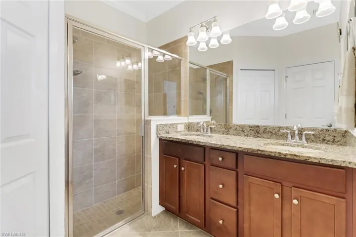 Bathroom with tile patterned floors, vanity, crown molding, and walk in shower