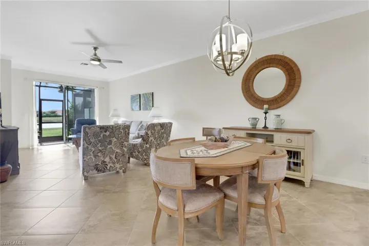 Tiled dining space featuring crown molding and ceiling fan with notable chandelier