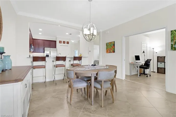 Dining room featuring light tile patterned floors, ornamental molding, and an inviting chandelier