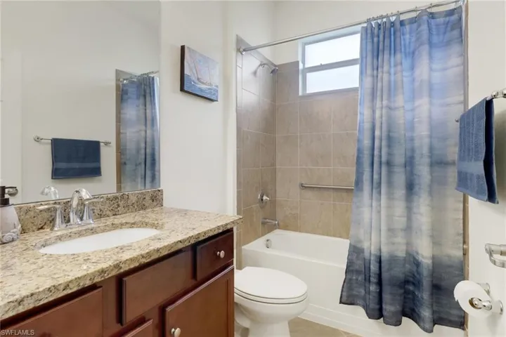 Full bathroom with vanity, shower / bath combo, and toilet