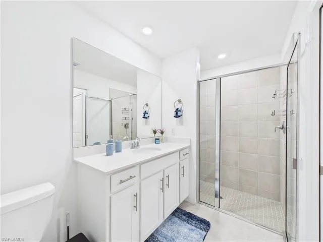 Full bath featuring vanity, a shower stall, tile patterned floors, and recessed lighting