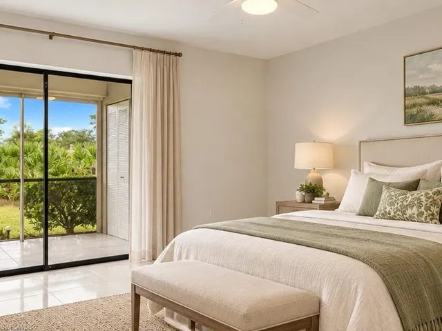 Neutral-toned interior featuring large-format ceramic tile flooring, ceiling fan, and floor-to-ceiling sliding glass doors leading to a screened lanai with landscape scenery