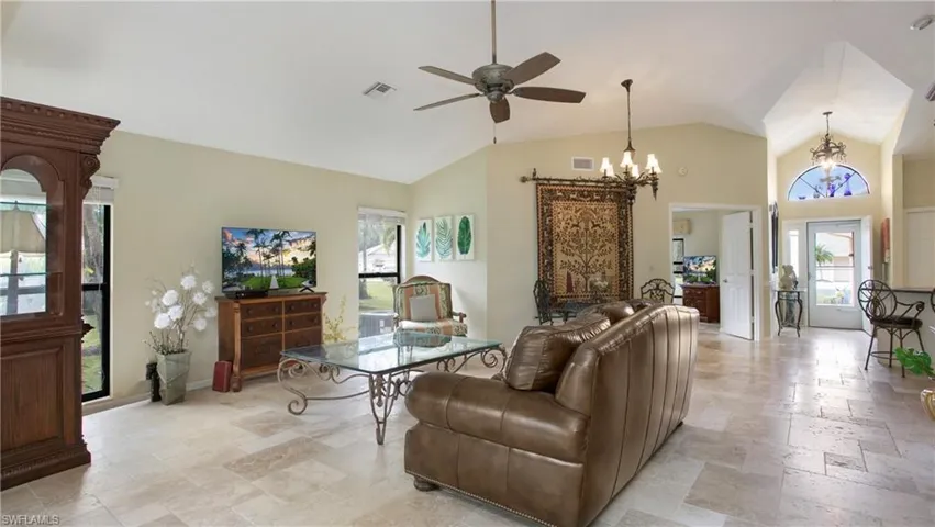 Living room featuring ceiling fan with notable chandelier and vaulted ceiling