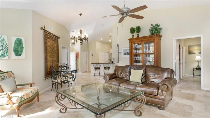 Living room featuring ceiling fan with notable chandelier and high vaulted ceiling