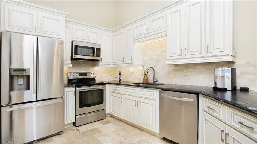 Kitchen featuring sink, appliances with stainless steel finishes, dark stone counters, and white cabinetry