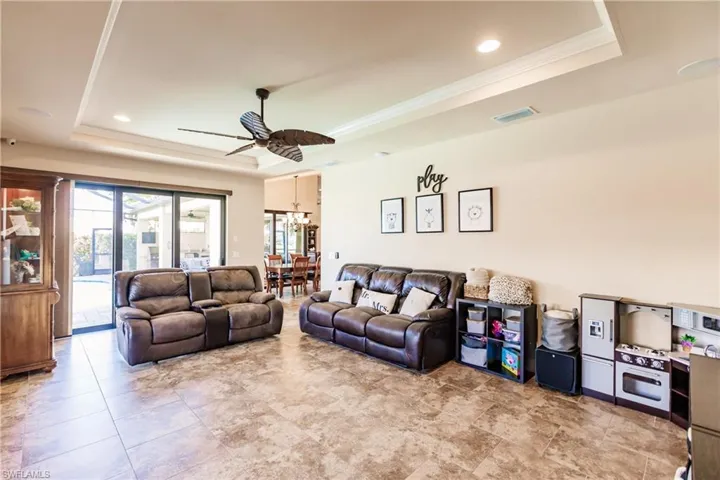Family room with crown molding, ceiling fan with notable chandelier, and a tray ceiling