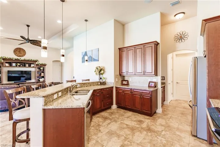 Kitchen with a breakfast bar, light granite counters, decorative light fixtures, and kitchen peninsula